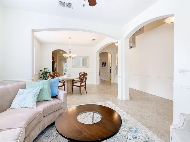 tiled living room featuring ceiling fan with notable chandelier