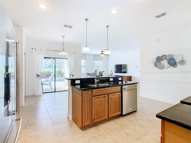 kitchen featuring ceiling fan, an island with sink, hanging light fixtures, sink, and appliances with stainless steel finishes