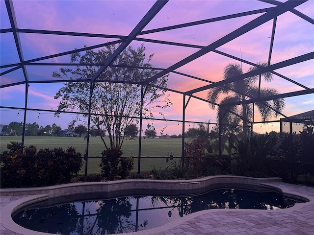 pool at dusk with a lanai and a patio