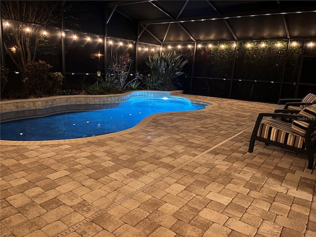 view of pool with glass enclosure and a patio area