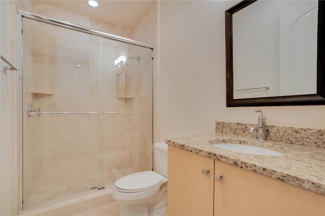 bathroom with vanity, toilet, and a shower with door