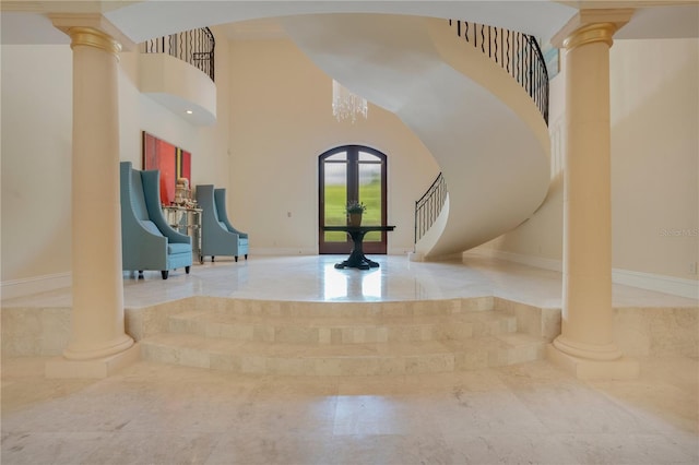 foyer entrance with a chandelier, a towering ceiling, and french doors