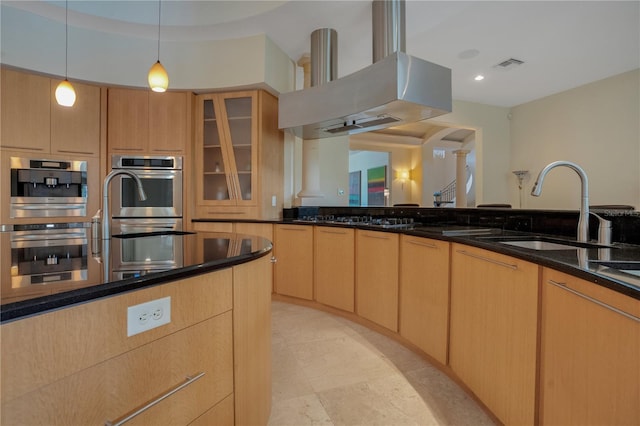 kitchen featuring sink, dark stone counters, pendant lighting, island range hood, and light brown cabinetry