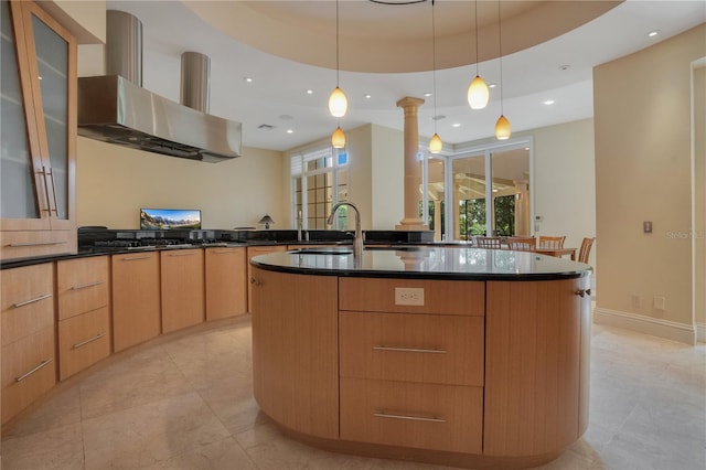 kitchen with a tray ceiling, pendant lighting, and wall chimney range hood