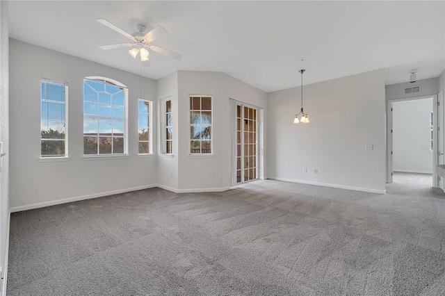 carpeted empty room featuring ceiling fan with notable chandelier