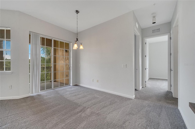 carpeted empty room featuring an inviting chandelier