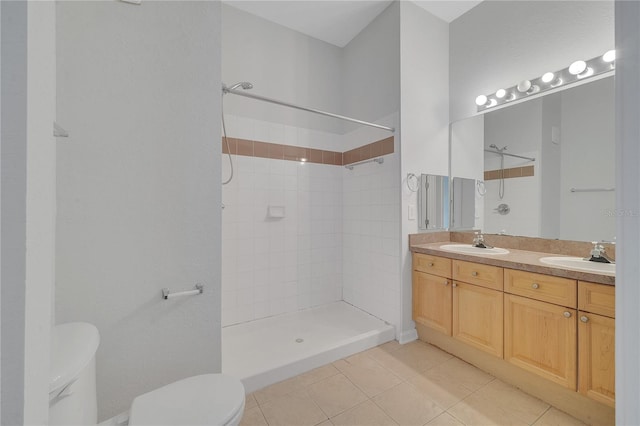 bathroom with a tile shower, tile patterned flooring, vanity, and toilet