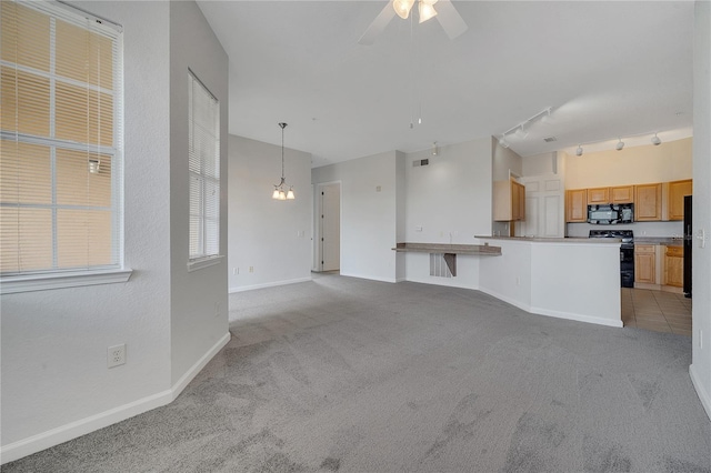 unfurnished living room with light carpet, ceiling fan with notable chandelier, and track lighting