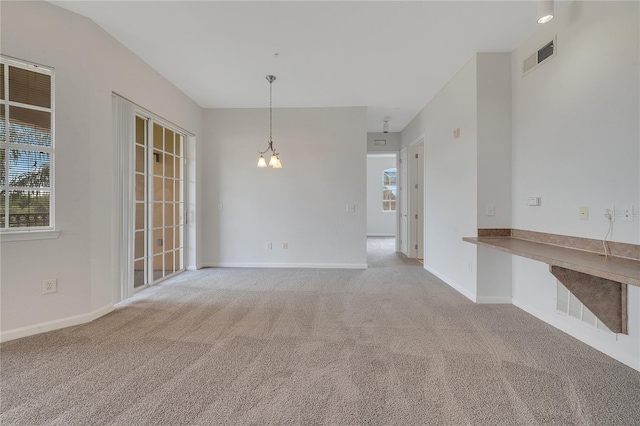 empty room featuring light colored carpet and a notable chandelier