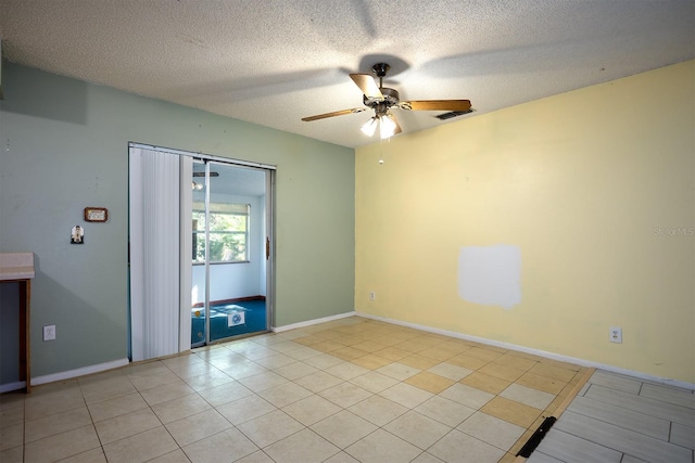 empty room with ceiling fan, a textured ceiling, and light tile patterned floors