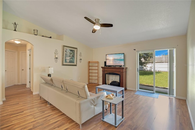 living room featuring light hardwood / wood-style floors, a textured ceiling, vaulted ceiling, and ceiling fan