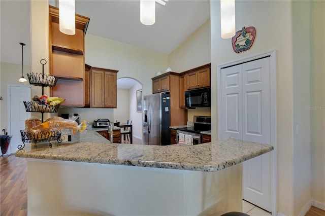 kitchen with appliances with stainless steel finishes, light wood-type flooring, kitchen peninsula, lofted ceiling, and pendant lighting