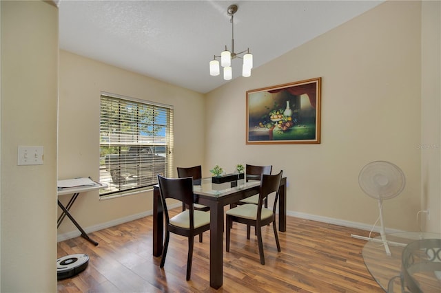 dining room with a chandelier, wood-type flooring, and vaulted ceiling