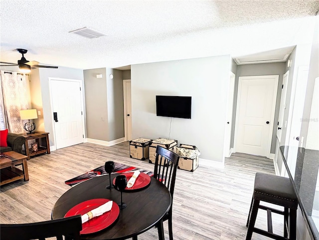 living room with ceiling fan, light hardwood / wood-style floors, and a textured ceiling