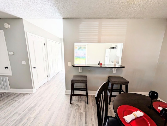 dining area with light hardwood / wood-style floors and a textured ceiling