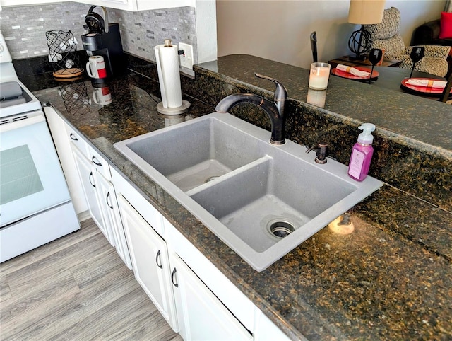 kitchen featuring decorative backsplash, electric range, sink, and white cabinets