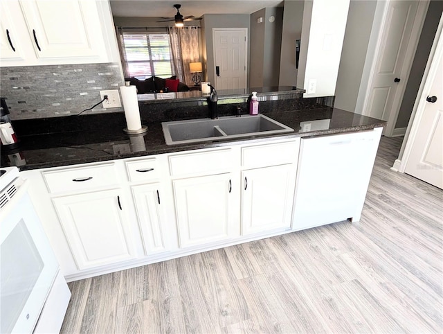 kitchen featuring kitchen peninsula, white appliances, sink, dark stone countertops, and white cabinets