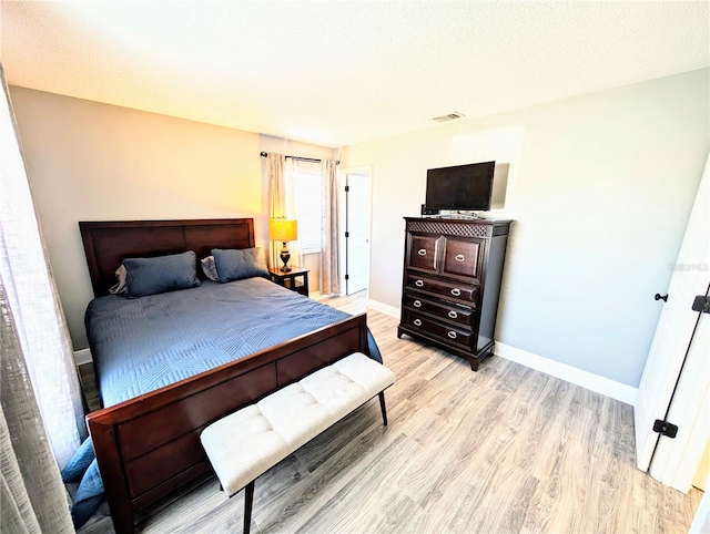 bedroom featuring a textured ceiling and light hardwood / wood-style flooring