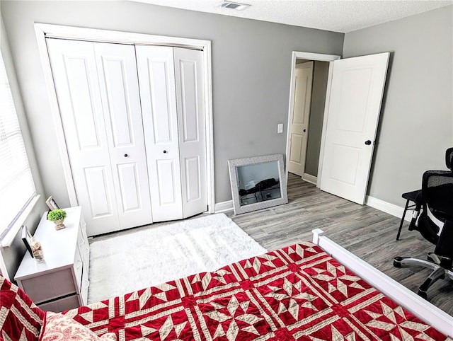 bedroom with a closet, wood-type flooring, and a textured ceiling