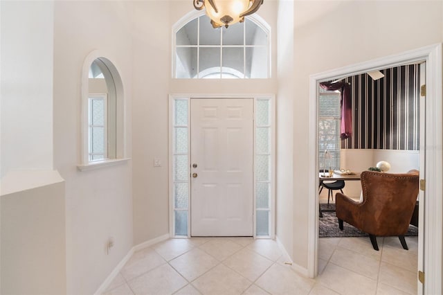 foyer entrance with a towering ceiling, baseboards, and light tile patterned flooring