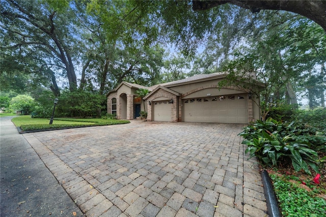 view of front of house featuring a garage, decorative driveway, and brick siding