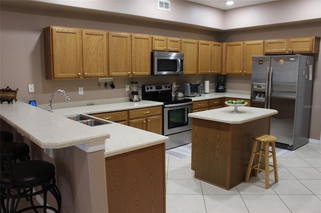 kitchen featuring stainless steel appliances, sink, kitchen peninsula, a kitchen bar, and light tile patterned floors