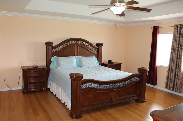 bedroom featuring a raised ceiling, ornamental molding, hardwood / wood-style floors, and ceiling fan