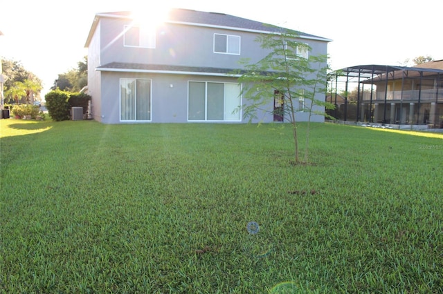 back of house featuring a lanai, central AC, and a lawn