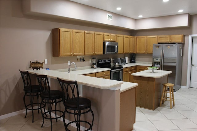 kitchen with light tile patterned floors, stainless steel appliances, kitchen peninsula, and a breakfast bar