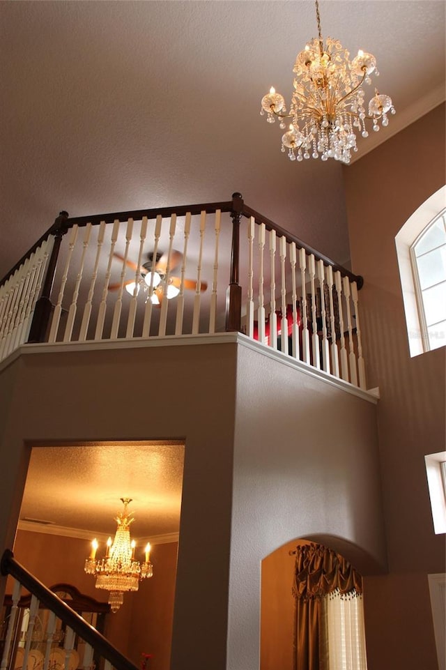 staircase with a towering ceiling, ornamental molding, and a chandelier