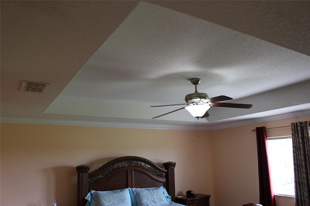 bedroom with ornamental molding, ceiling fan, a textured ceiling, and a raised ceiling