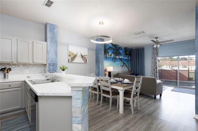 kitchen featuring wood-type flooring, kitchen peninsula, decorative light fixtures, and sink