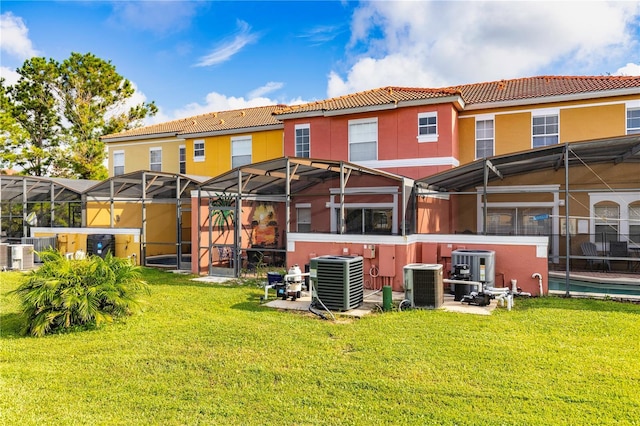3052 Secret Lake Dr, Kissimmee, FL 34747 - rear view of property with a tiled roof, glass enclosure, stucco siding, and a yard
