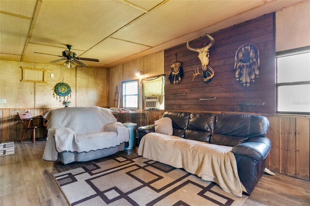 living room featuring cooling unit, wood walls, ceiling fan, and hardwood / wood-style flooring