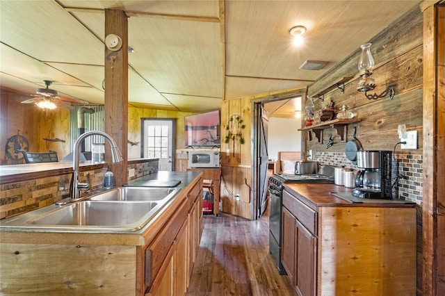 kitchen with electric stove, wooden walls, sink, and ceiling fan