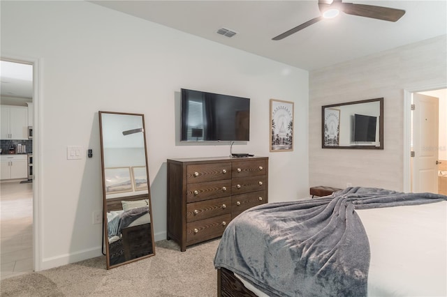 bedroom featuring baseboards, light carpet, ensuite bath, visible vents, and ceiling fan