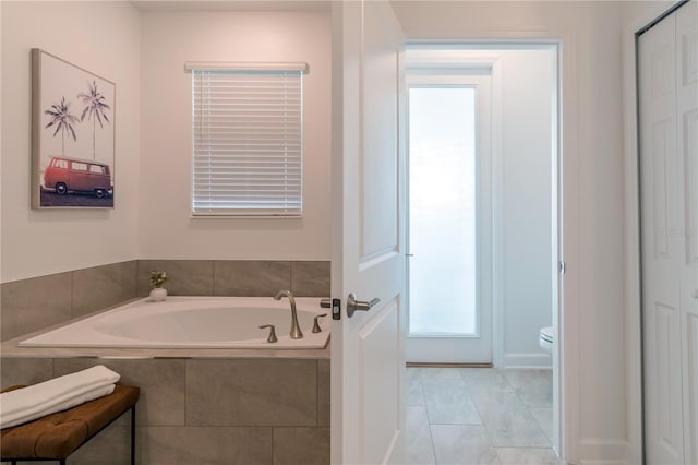 bathroom featuring toilet, a bath, and tile patterned floors