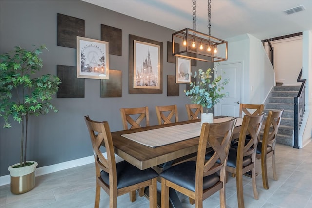 dining space with visible vents, baseboards, light tile patterned flooring, and stairs