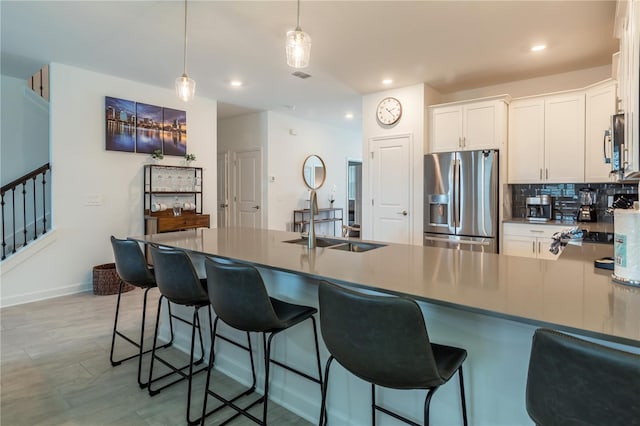kitchen featuring stainless steel appliances, white cabinets, a sink, and decorative backsplash