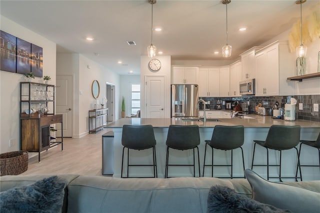 kitchen featuring a peninsula, backsplash, visible vents, and stainless steel appliances
