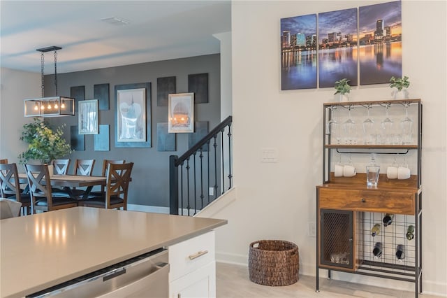 kitchen featuring visible vents, baseboards, dishwasher, white cabinetry, and pendant lighting