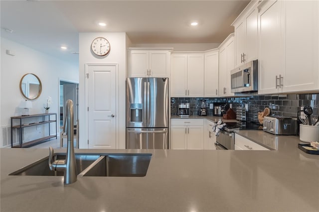 kitchen featuring tasteful backsplash, white cabinets, a sink, dark countertops, and stainless steel appliances