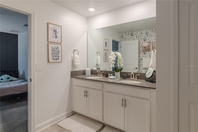 bathroom featuring a sink, ensuite bathroom, baseboards, and double vanity