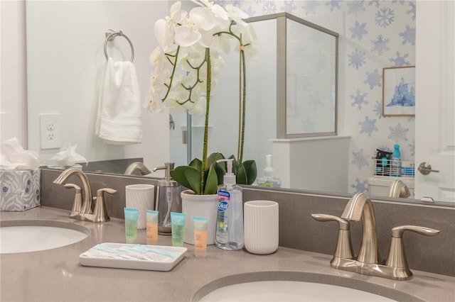 full bathroom featuring a tile shower, wallpapered walls, double vanity, and a sink