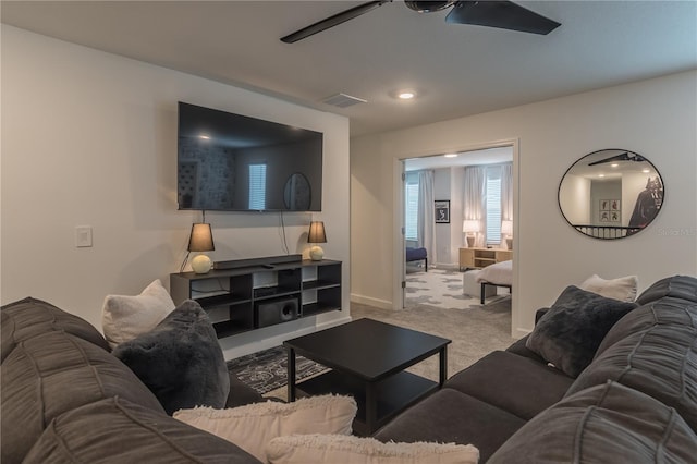 carpeted living area with ceiling fan, baseboards, and visible vents