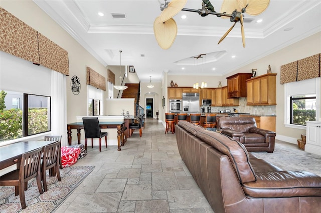 living room featuring a raised ceiling and ornamental molding