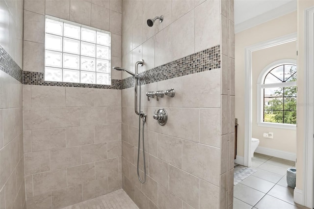 bathroom featuring crown molding, tiled shower, toilet, and tile patterned flooring