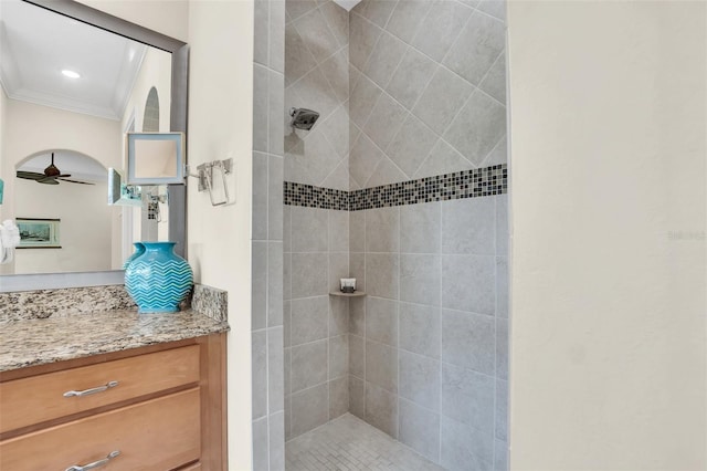 bathroom with ceiling fan, crown molding, vanity, and tiled shower