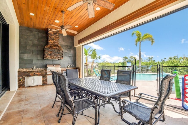 view of patio / terrace featuring a grill, ceiling fan, a fenced in pool, and exterior kitchen