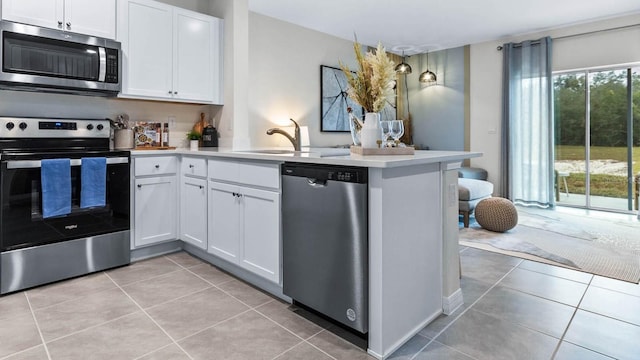 kitchen with white cabinetry, kitchen peninsula, appliances with stainless steel finishes, and sink